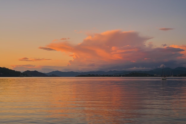 Paesaggio serale caldo della baia di Fethiye sfondo sfocato di una catena montuosa e nubi cumuliformi nei raggi del sole un'idea per uno sfondo