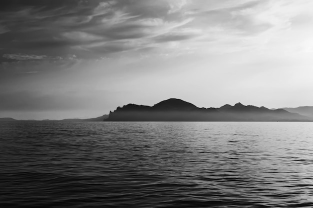 Paesaggio serale estivo con mare e catena montuosa nebbiosa