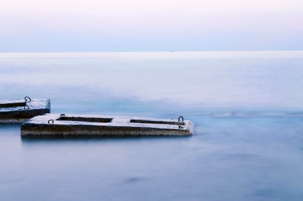 Paesaggio tranquillo con strutture in cemento in acqua di mare al crepuscolo