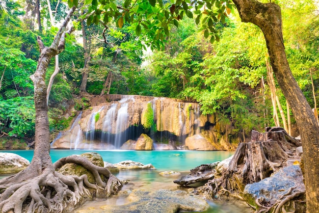 Paesaggio tropicale con bellissime cascate di rocce di lago color smeraldo e grandi radici di alberi nella foresta selvaggia della giungla Parco nazionale di Erawan Kanchanaburi Thailandia
