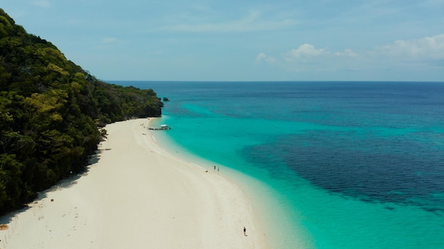 Paesaggio tropicale spiaggia sabbiosa con palme e acque turchesi della barriera corallina vista dall'alto puka