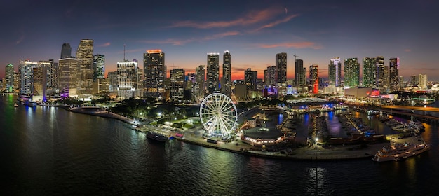 Paesaggio urbano americano di notte Marina di Miami e Skyviews Observation Wheel al Bayside Marketplace con riflessi nell'acqua della Baia di Biscayne e grattacieli del centro finanziario della città di Brickell