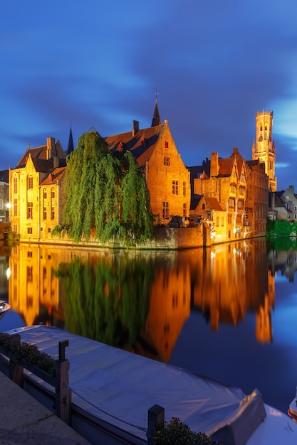 Paesaggio urbano panoramico con una città da favola medievale e torre Belfort dalla banchina Rosario, Rozenhoedkaai, di notte a Bruges, Belgio
