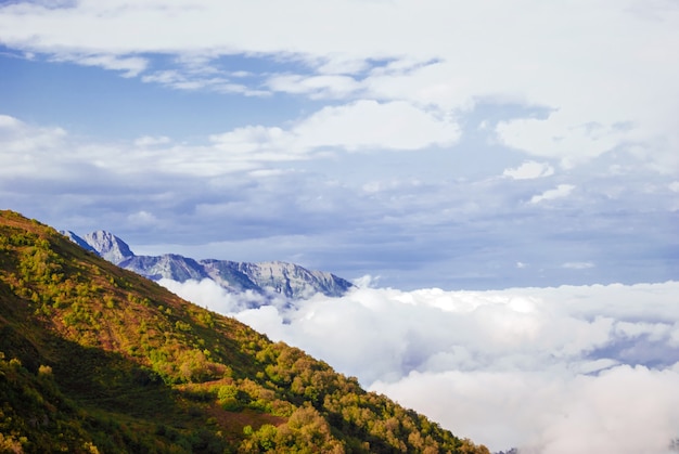 Paesaggio - vista dal passo di montagna in una giornata di sole sulla valle nascosta da nuvole basse