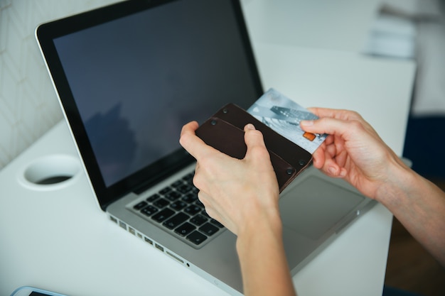 Pagamento online, le mani della donna in possesso di una carta di credito e l&#39;utilizzo di smart phone per lo shopping online