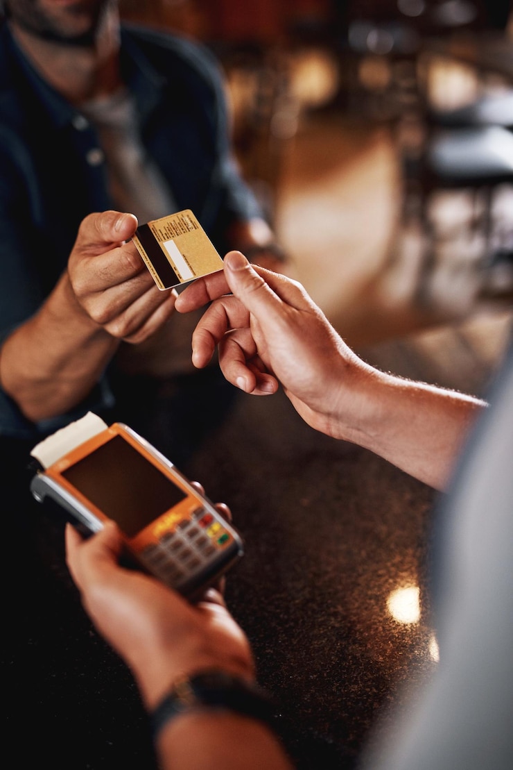 Foto pagherò con plastica grazie primo piano di una persona irriconoscibile che effettua un pagamento a un barman tramite l'uso di una carta di credito all'interno di una fabbrica di birra durante il giorno