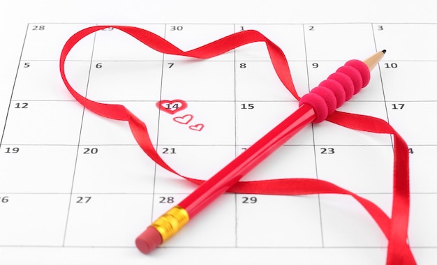 Pagina del calendario con cuori, matita e nastro il giorno di San Valentino