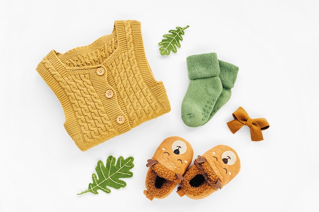 Pagliaccetto giallo lavorato a maglia, calzini e simpatiche pantofole per bambini. Set di vestiti e accessori per neonati. Disposizione piatta, vista dall'alto