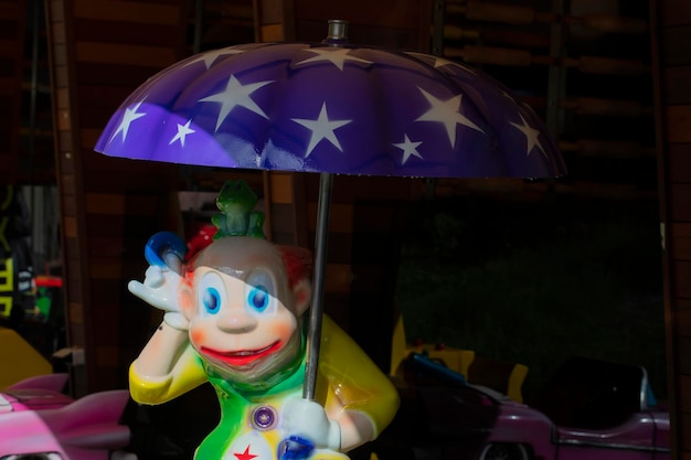Pagliaccio luminoso giocattolo sotto un ombrello blu
