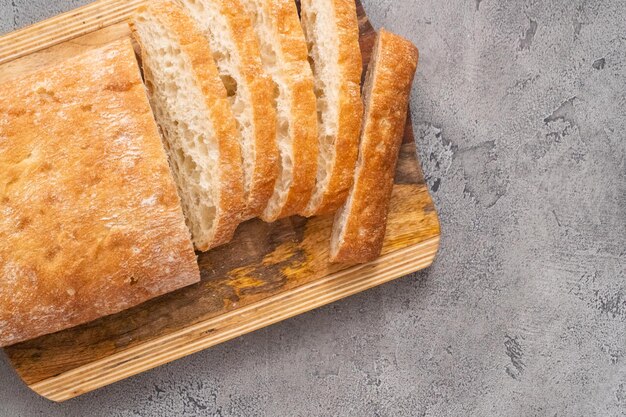 Pagnotta affettata di pane ciabatta appena sfornato sul tavolo grigio.