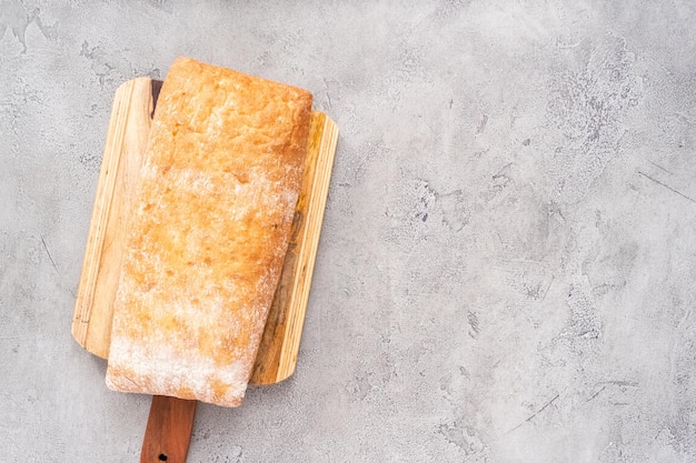 Pagnotta di ciabatta appena sfornata sul tavolo grigio.