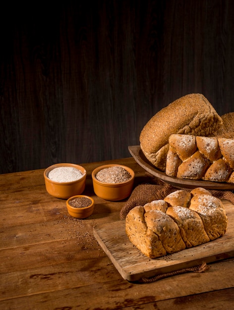Pagnotta di pane a base di semi di sesamo (gergelim) su tavola di legno rustico con altri pani e ingredienti in background.