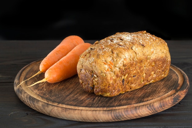 Pagnotta di pane alle carote sano su una tavola di legno rotonda