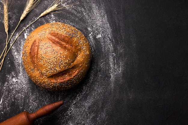 Pagnotta di pane bianco rotondo con semi di sesamo e semi di papavero su uno spazio nero. copia spazio