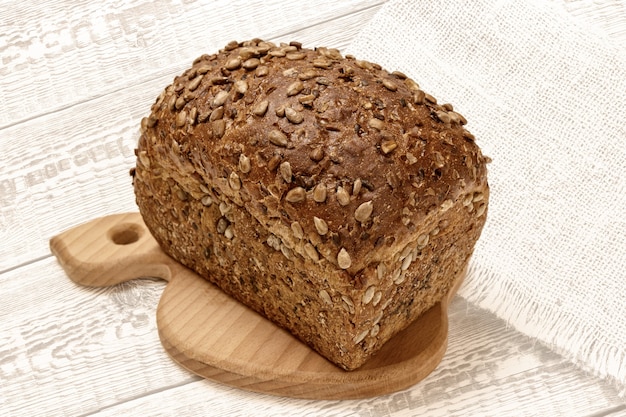 Pagnotta di pane di segale su tagliere di legno con superficie in legno bianco