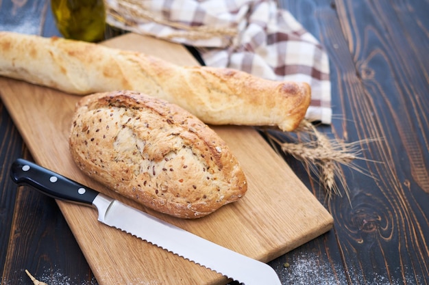 Pagnotta di pane fresco e baguette sul tagliere di legno al tavolo della cucina