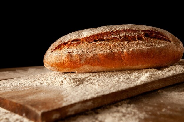 Pagnotta di pane su una tavola su fondo scuro Pane cotto con una crosta calda