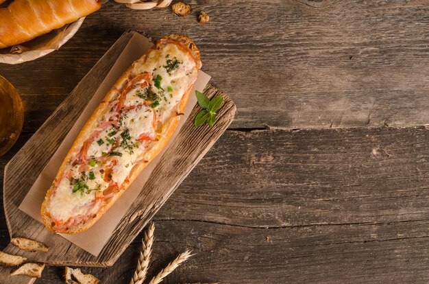 Pagnotta farcita con formaggio e pomodori su uno sfondo di legno con ingredienti con spazio di copia