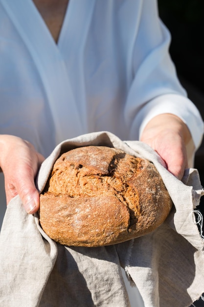 Pagnotta fresca di pane di segale fatto in casa nelle mani della donna