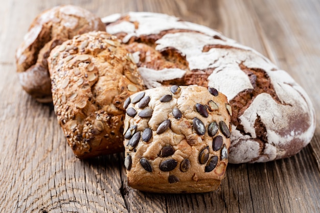 Pagnotte croccanti rustiche dell'oro e focacce su fondo di legno