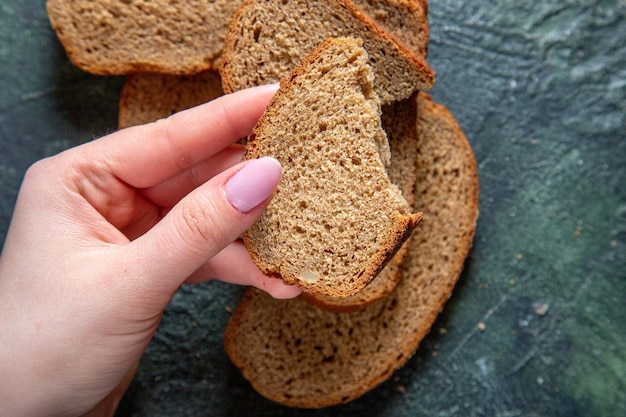 Pagnotte di pane scuro vista dall'alto con strappo femminile sulla scrivania scura