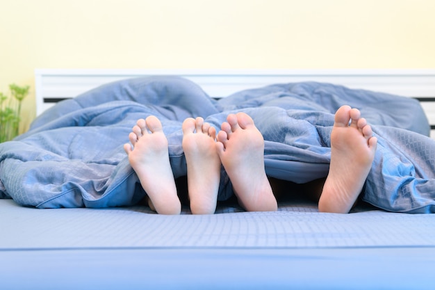 paia di piedi di bambini. Fratello e sorella che si trovano sotto la coperta