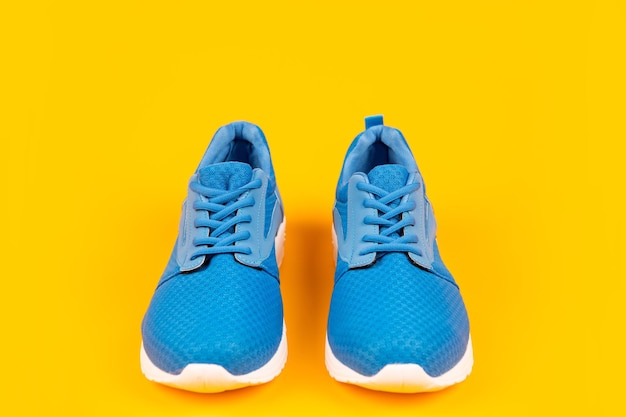 Paio di comode scarpe sportive blu su sfondo giallo abbigliamento sportivo