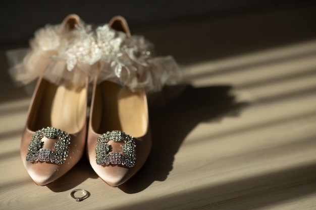 Paio di scarpe da sposa rosa e anello di nozze sul pavimento