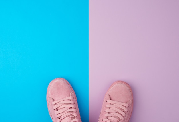 Paio di scarpe sportive rosa con lacci su sfondo blu, vista dall'alto, posto per il testo