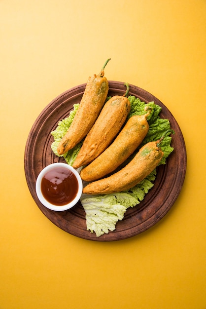 Pakora o Mirchi Bajji di peperoncino verde croccante, servito con ketchup su sfondo lunatico. È un popolare spuntino per l'ora del tè dall'India, specialmente nei monsoni. Messa a fuoco selettiva