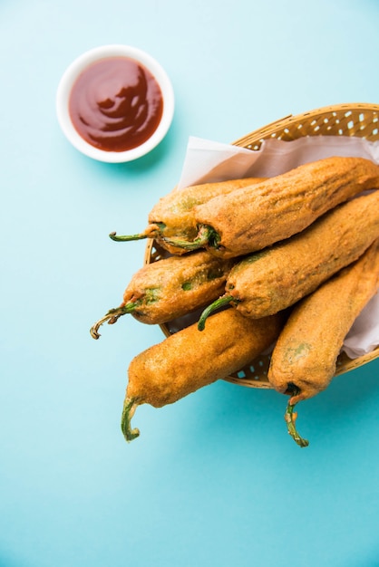 Pakora o Mirchi Bajji di peperoncino verde croccante, servito con ketchup su sfondo lunatico. È un popolare spuntino per l'ora del tè dall'India, specialmente nei monsoni. Messa a fuoco selettiva