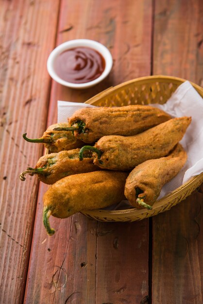 Pakora o Mirchi Bajji di peperoncino verde croccante, servito con ketchup su sfondo lunatico. È un popolare spuntino per l'ora del tè dall'India, specialmente nei monsoni. Messa a fuoco selettiva