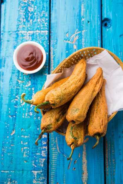 Pakora o Mirchi Bajji di peperoncino verde croccante, servito con ketchup su sfondo lunatico. È un popolare spuntino per l'ora del tè dall'India, specialmente nei monsoni. Messa a fuoco selettiva