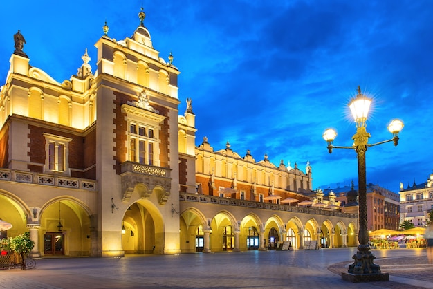 Palazzo illuminato sulla piazza della città vecchia di notte con cielo blu scuro. Cracovia, Polonia