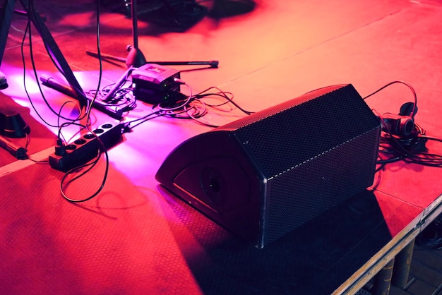 Palcoscenico del concerto sotto una luce rossa con un sacco di aste microfoniche a filo e un grande altoparlante sul pavimento