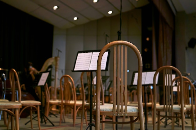 Palcoscenico vuoto della sala da concerto con sedie e spartiti musicali prima di un'esibizione di un'orchestra sinfonica