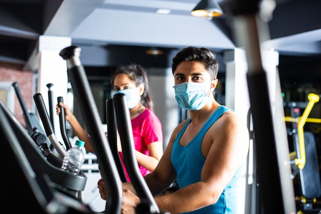 Palestra dopo la corona - La giovane coppia indiana che si allena in palestra dopo l'epidemia di corona, indossa una maschera protettiva