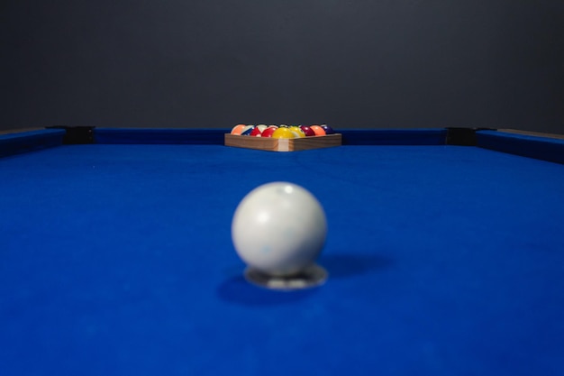 Palla bianca sfuocata pronta a colpire gli altri sul tavolo da biliardo blu.