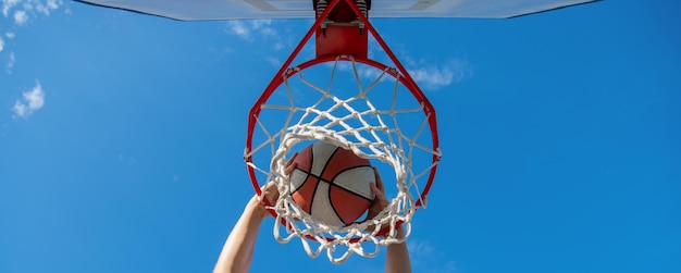 Palla da basket inzuppata attraverso l'anello netto con le mani che vincono