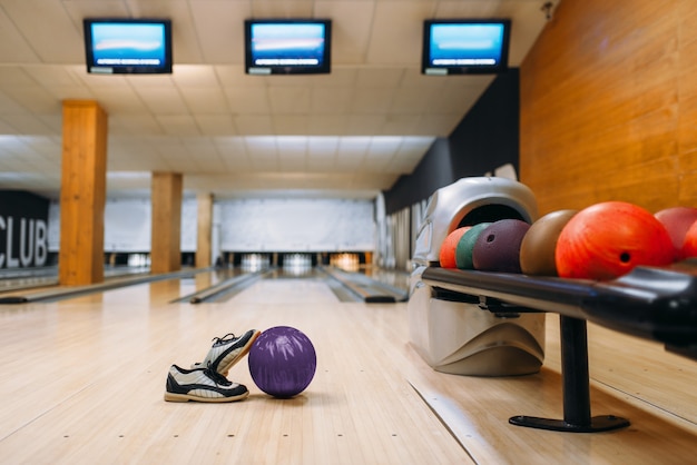 Palla da bowling e scarpe da casa sul pavimento di legno nel club, perni, nessuno. Concetto di gioco della ciotola, tenpin