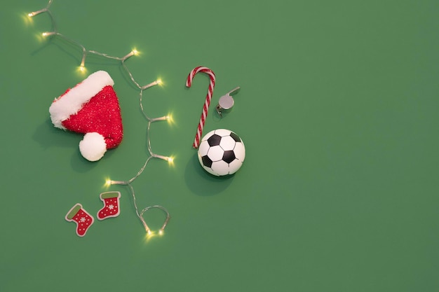 Palla da calcio a Natale Cappello di Babbo Natale su uno sfondo verde come un campo da calcio Natale nello sport
