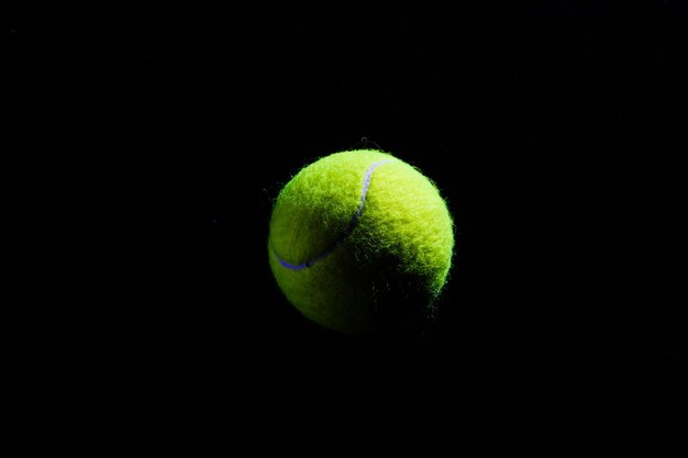 Palla da tennis isolata sul nero con illuminazione drammatica