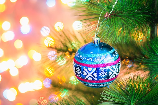 Palla di Natale blu su un albero di Natale su uno sfondo di luci ghirlande bokeh