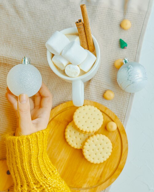 Palla di Natale della tenuta della ragazza per la decorazione con la cannella della caramella gommosa e molle del cacao, biscotti