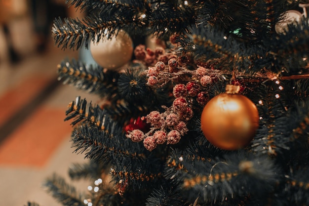 Palla di Natale dorata e bacche rosse appese all'albero di Natale Effetto magico Bokeh Festive