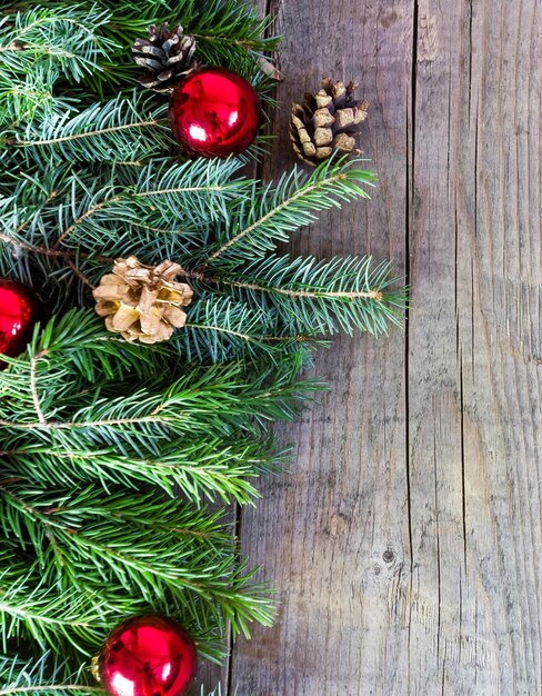 Palla di Natale e rami di albero di pelliccia con coni su fondo di legno