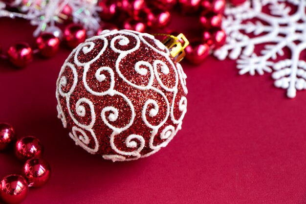 palla di Natale rossa su uno sfondo rosso intenso con perline rosse Sfondo di Natale con decorazioni