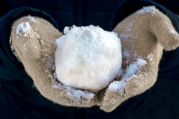 Palla di neve nelle mani di un bambino, divertimento invernale