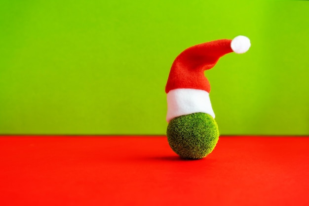 Palla di terra verde in un cappello da Babbo Natale. Una palla d'erba in un cappello di Capodanno.
