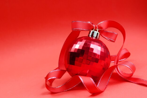 Palla rossa del giocattolo su un albero di Natale con un nastro rosso sul rosso